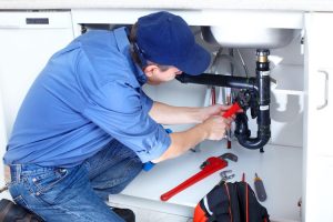 Plumber fixing a plumbing pipe under a sink